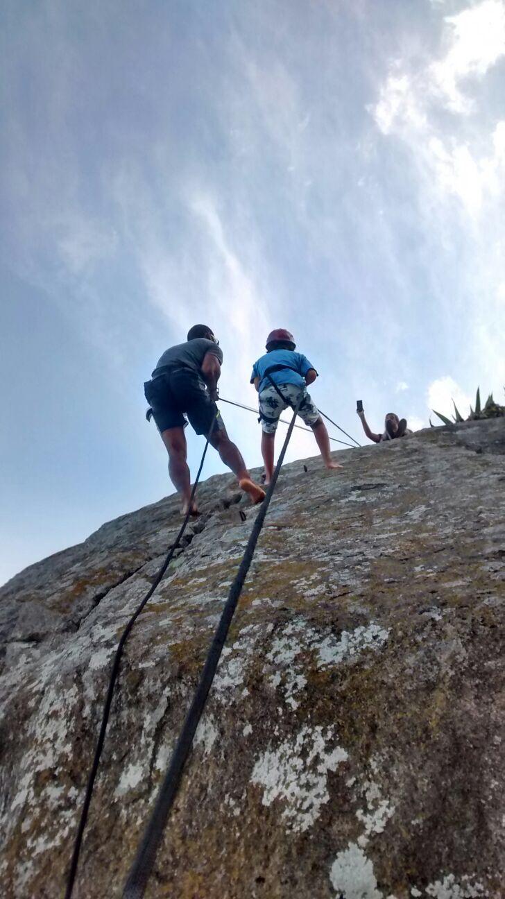 Vista ascendente de criança e terapeuta a escalar uma rocha
