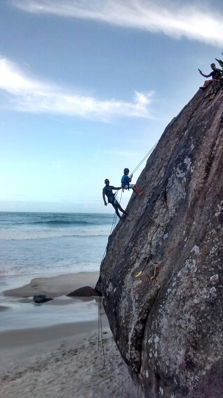 Terapeuta e criança a escalar rocha com vista para o oceano
